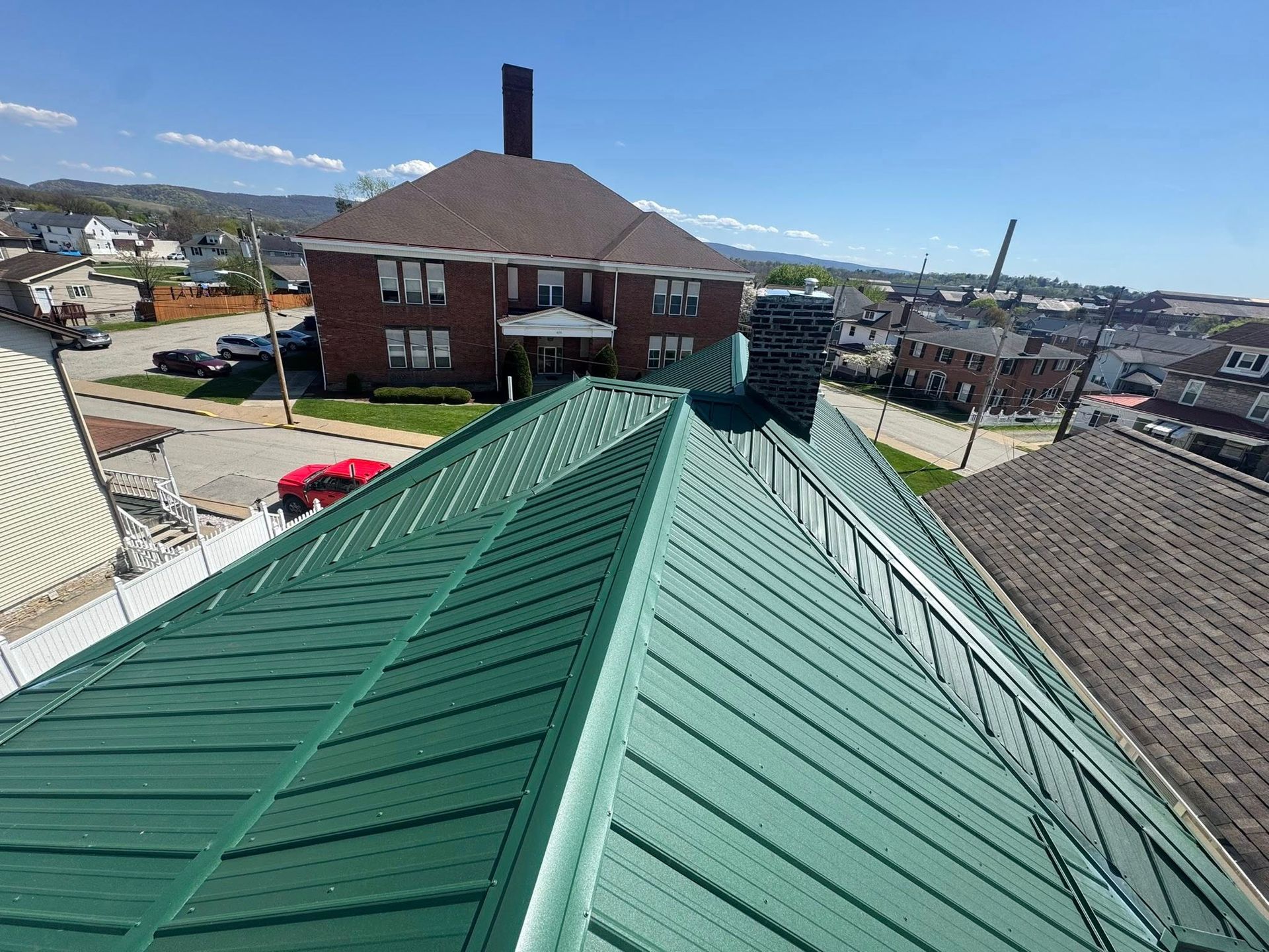 An aerial view of a green metal roof on a brick building.