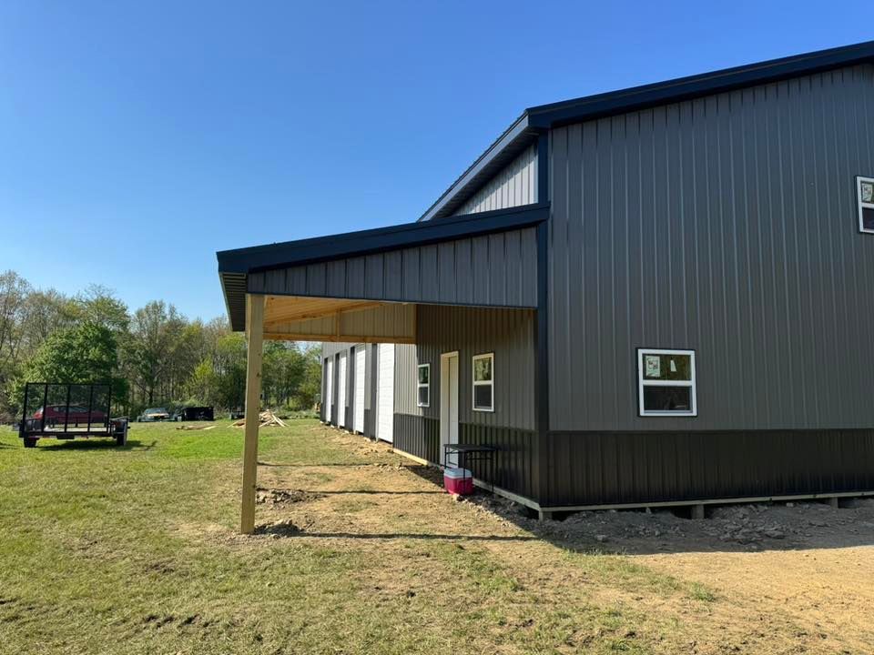 A large metal building with a porch and a truck parked in front of it.