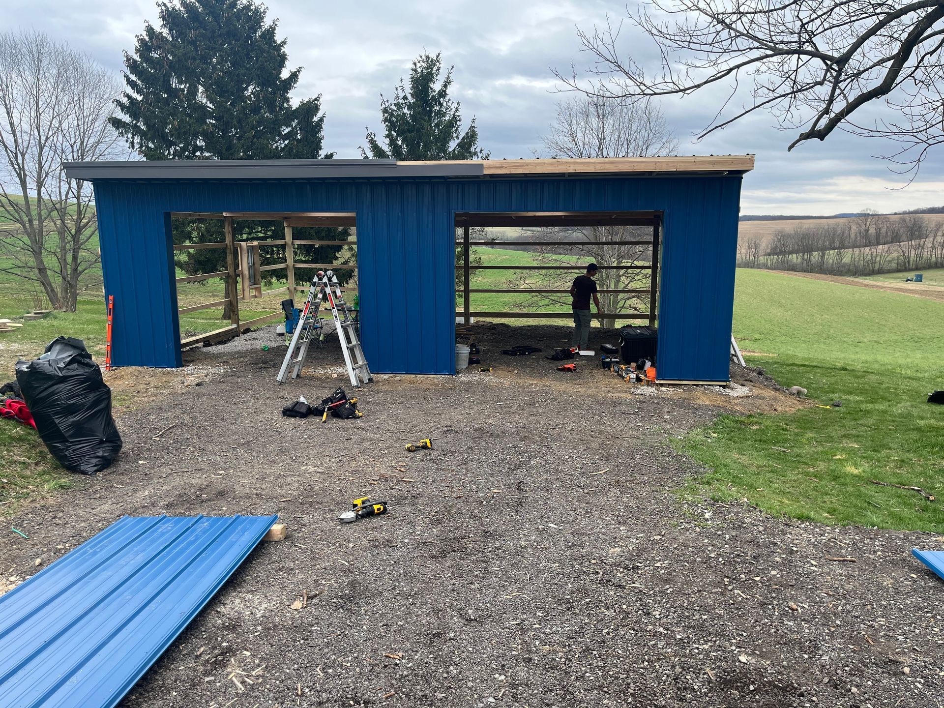 A blue garage is being built in the middle of a field.