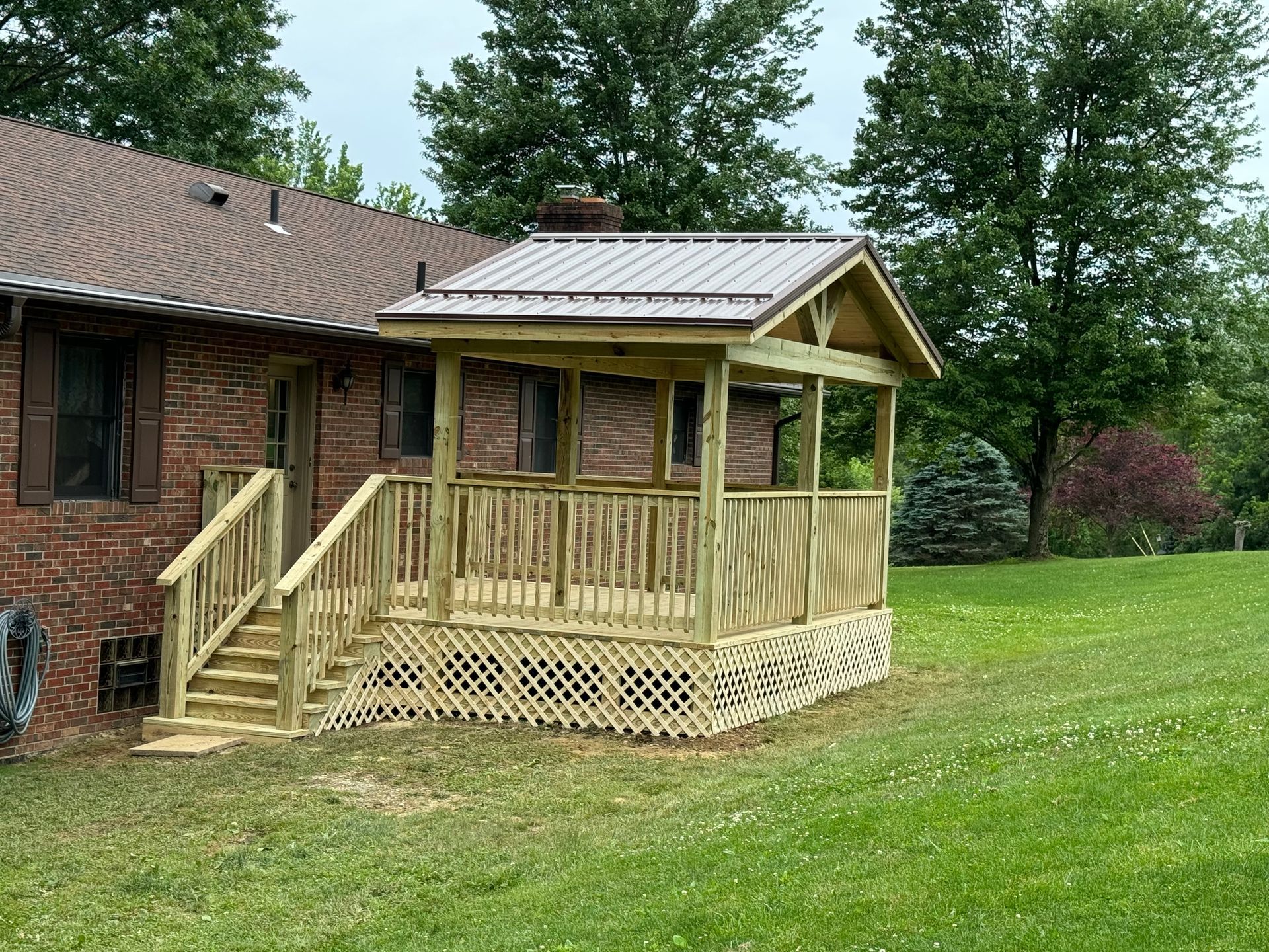 A wooden porch is sitting in front of a brick house.