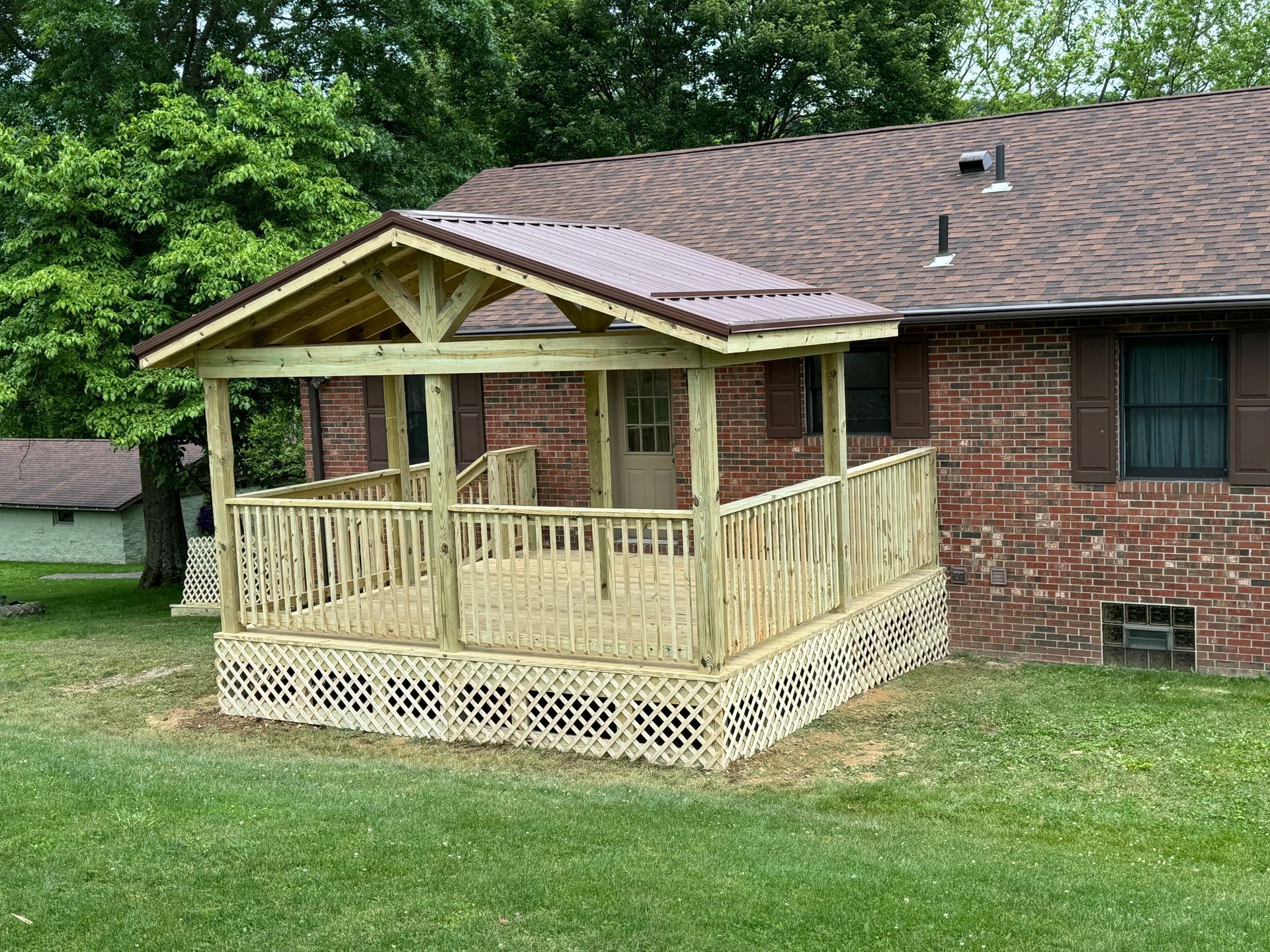 A wooden porch is sitting in front of a brick house.