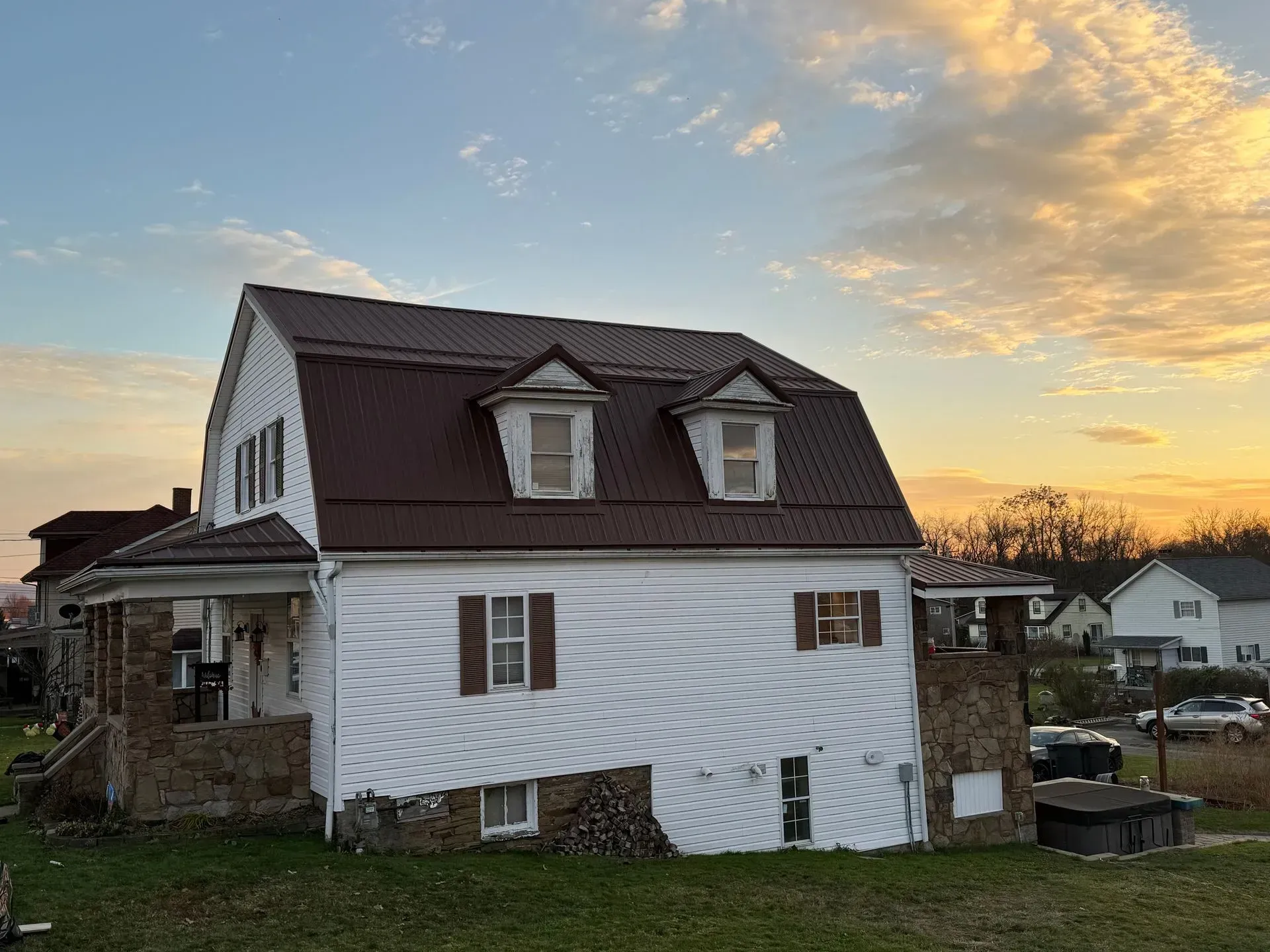 A white house with a brown roof is sitting on top of a lush green field.