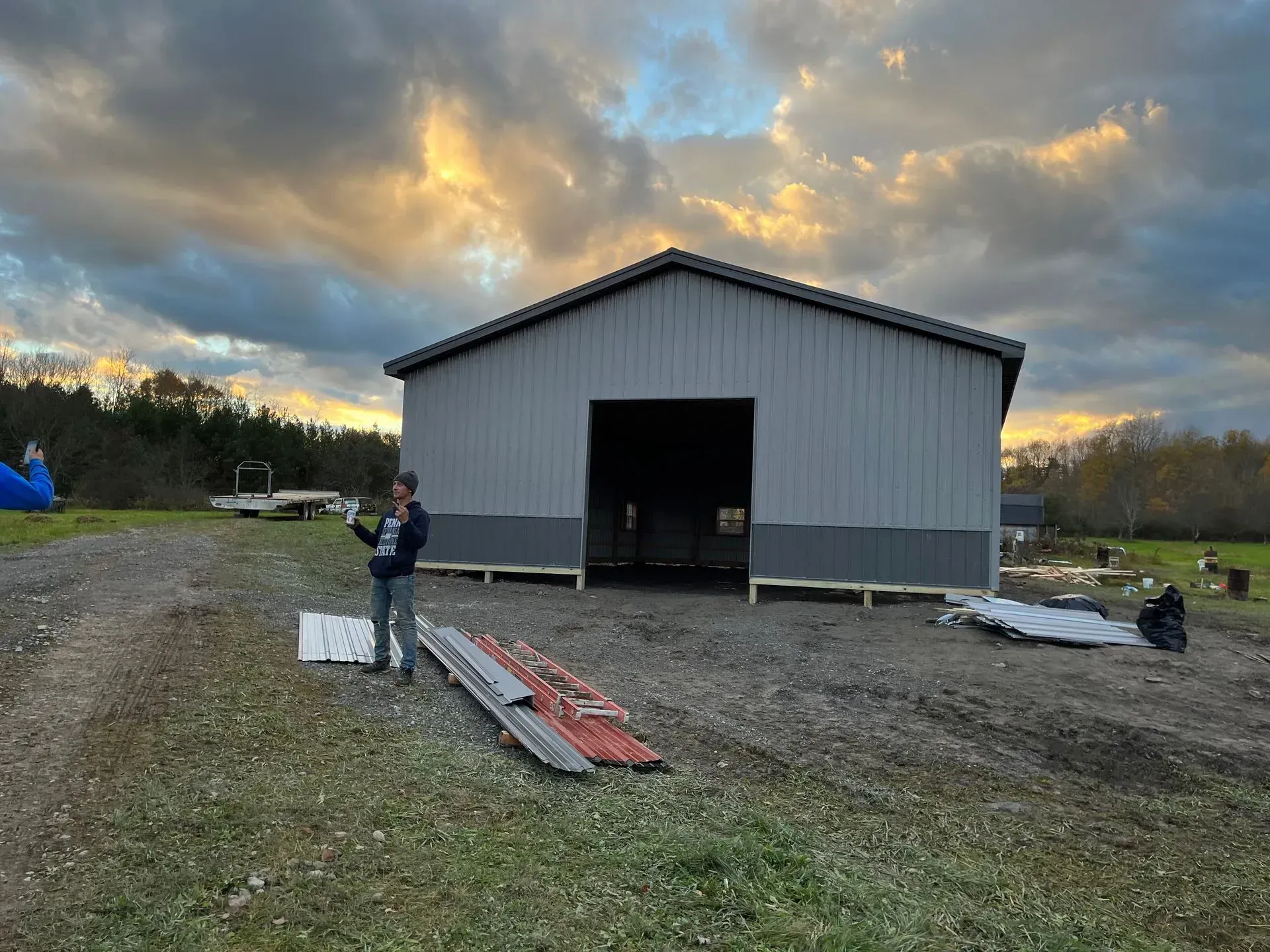 A man is standing in front of a large building in a field.