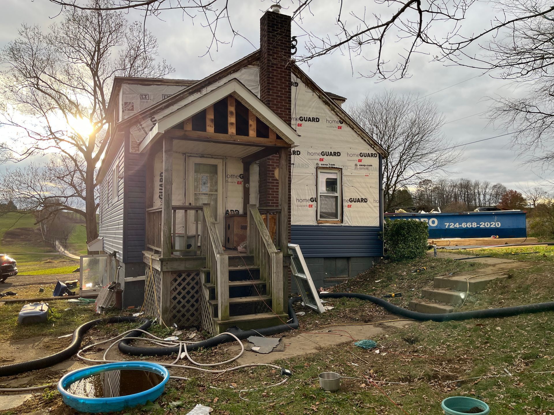 A small house is being remodeled in the middle of a field.