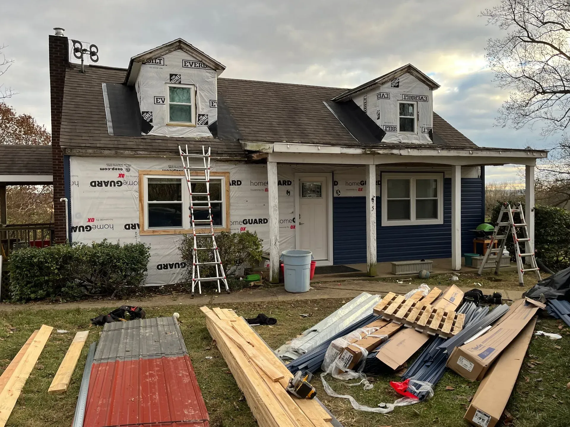 A house is being remodeled with a lot of wood in front of it.