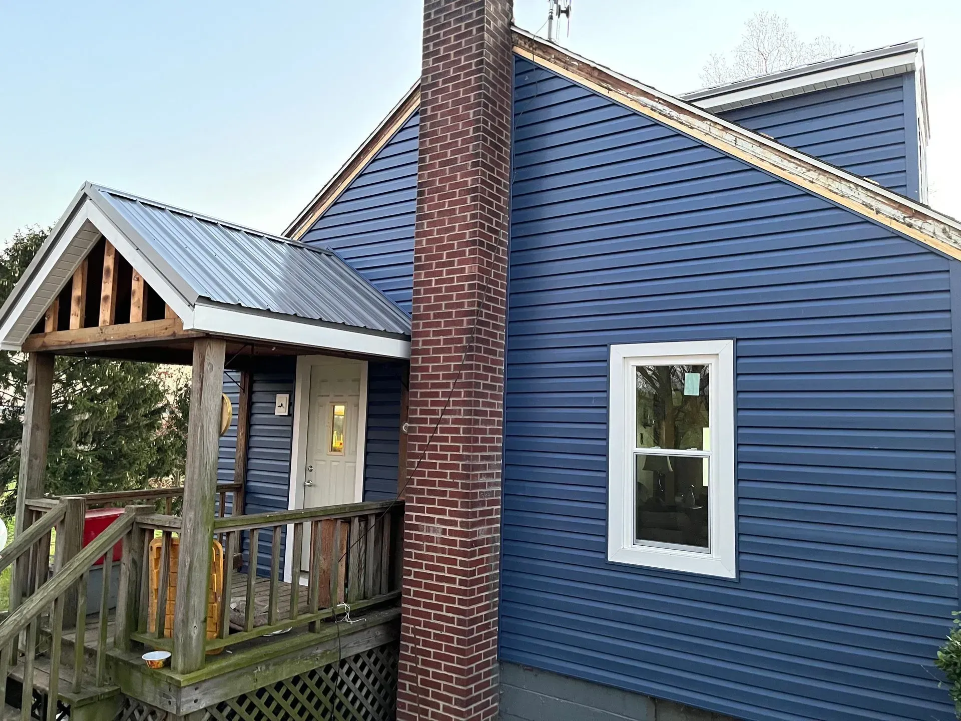 A blue house with a brick chimney and a porch.