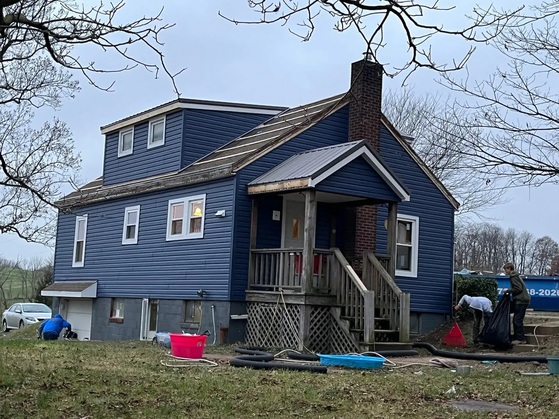 A blue house with a brick chimney is being remodeled
