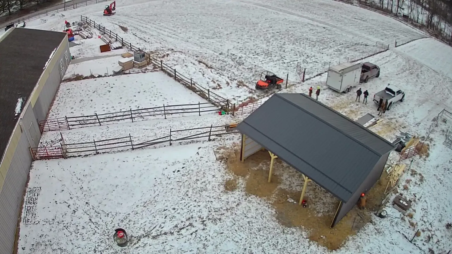 An aerial view of a snowy field with a building in the middle