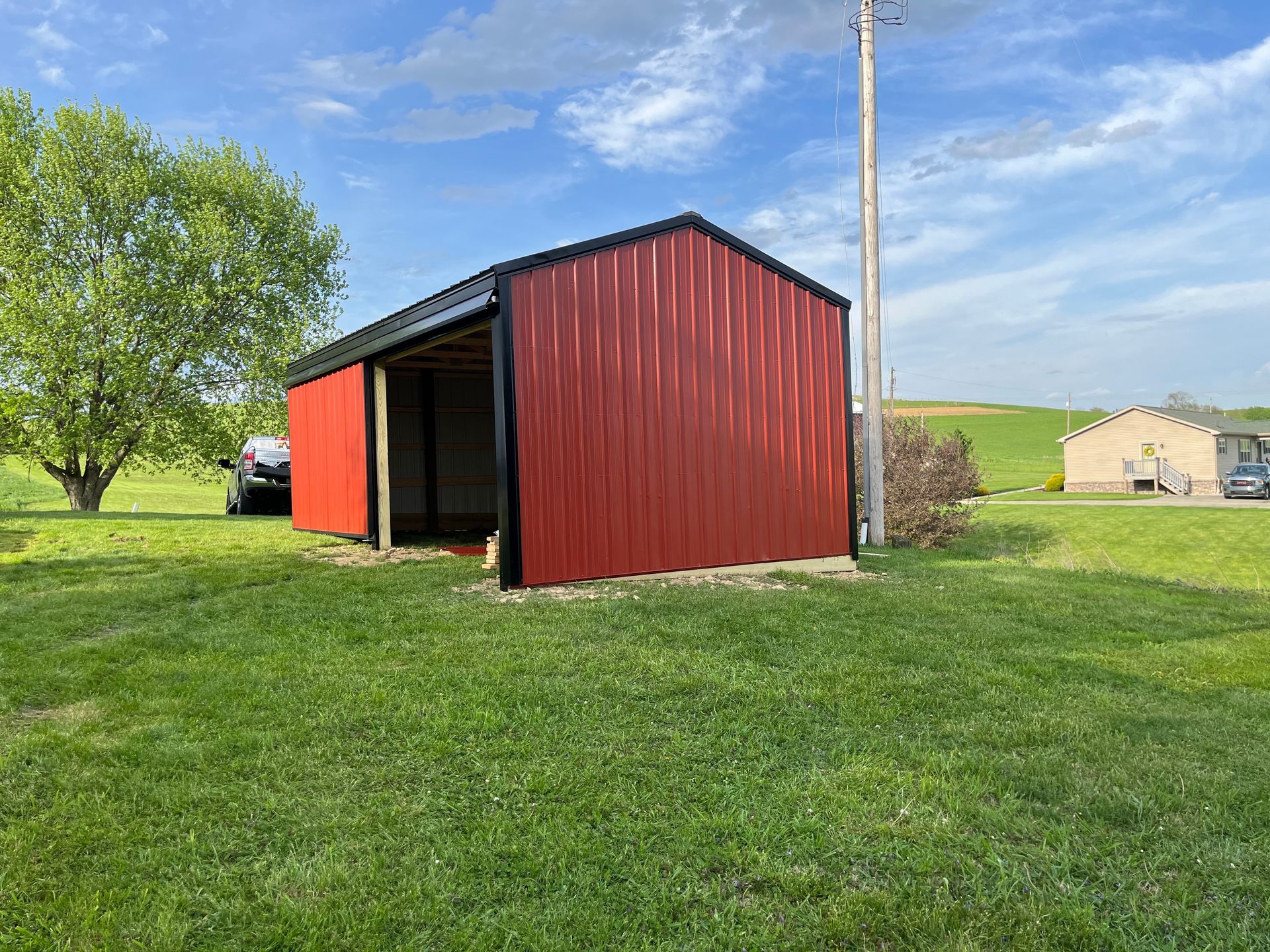 A red barn is sitting in the middle of a grassy field.