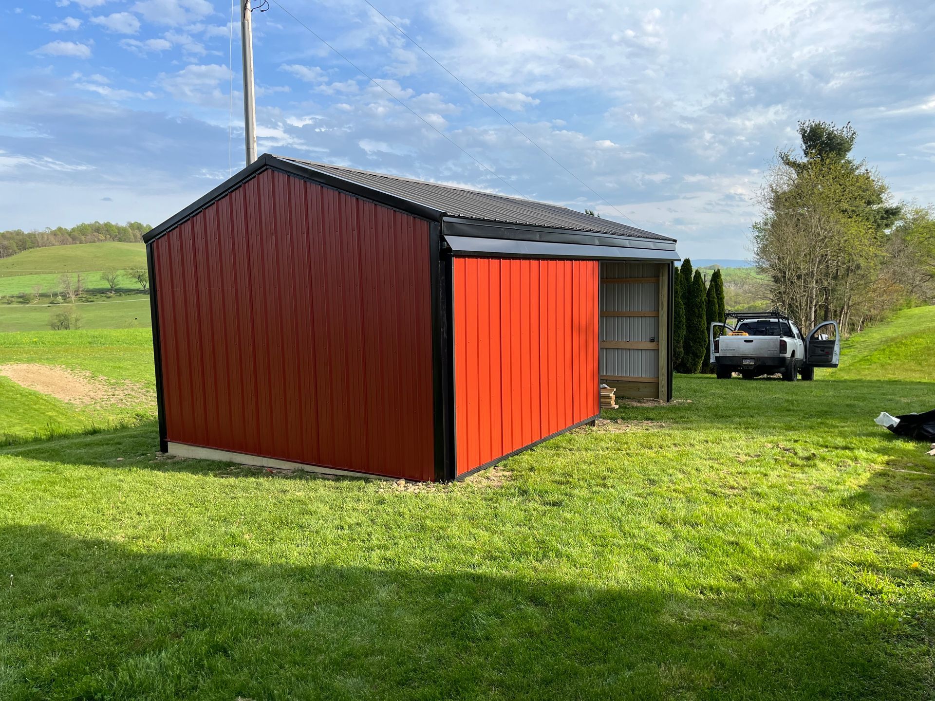 A red shed is sitting in the middle of a grassy field.