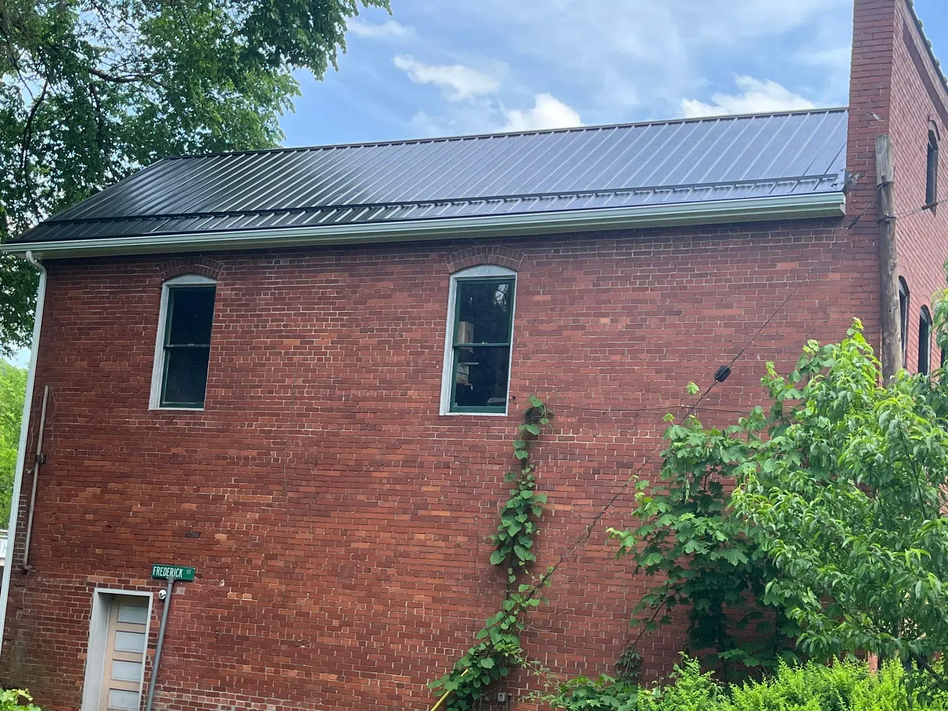 A brick building with a metal roof and a chimney.