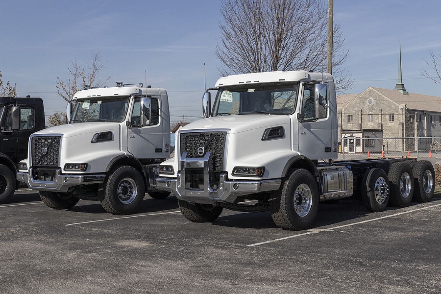 Two semi trucks are parked next to each other in a parking lot.