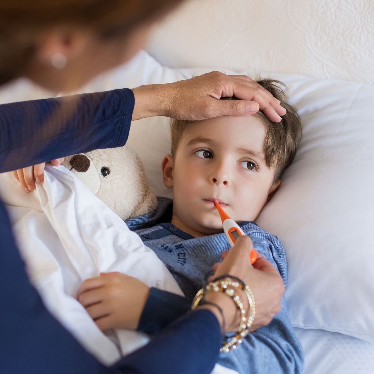 young boy in bed at home with a fever and flu symptoms