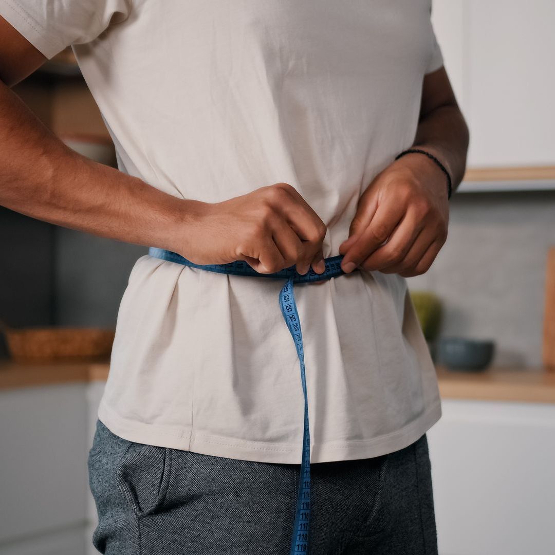 man measuring his waist after weight loss