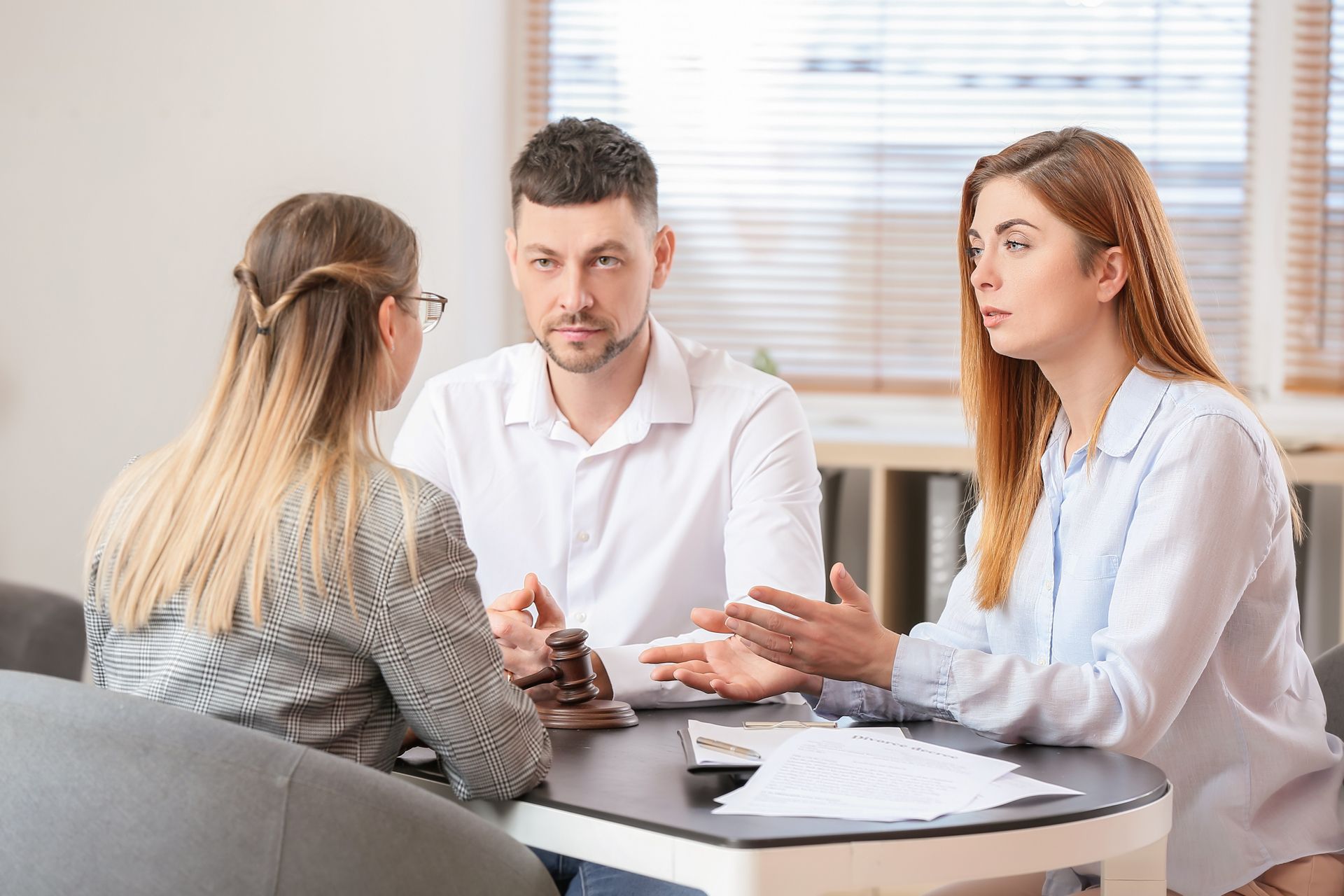 Three people at a table; a lawyer, and a couple; discussing documents.