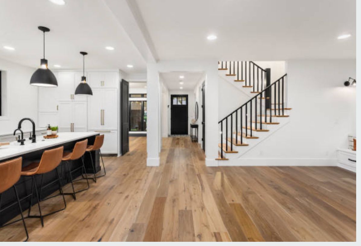 A kitchen with hardwood floors and a staircase leading to the second floor.