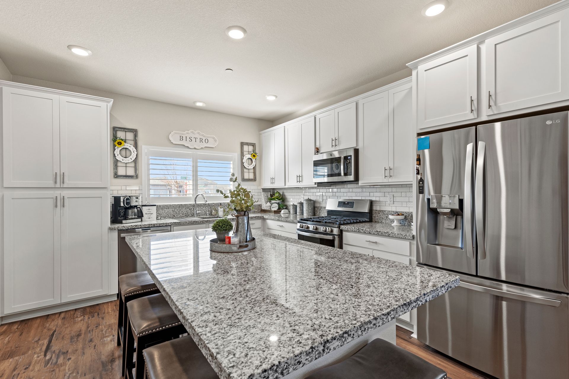 A kitchen with granite counter tops , stainless steel appliances , and white cabinets.