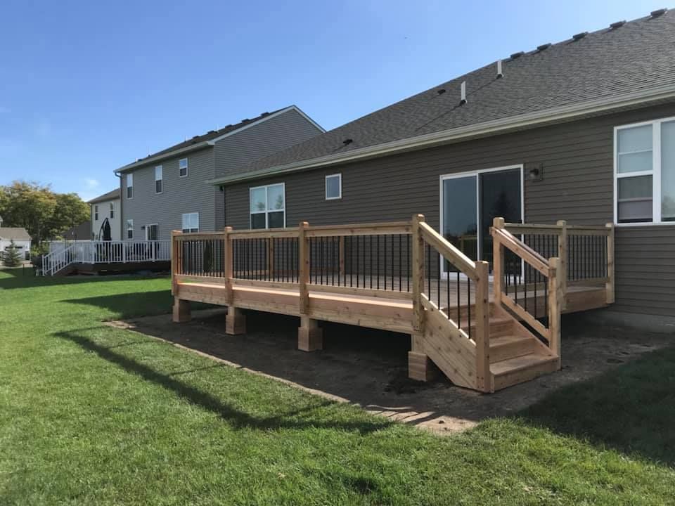 A wooden deck with stairs is in the backyard of a house.