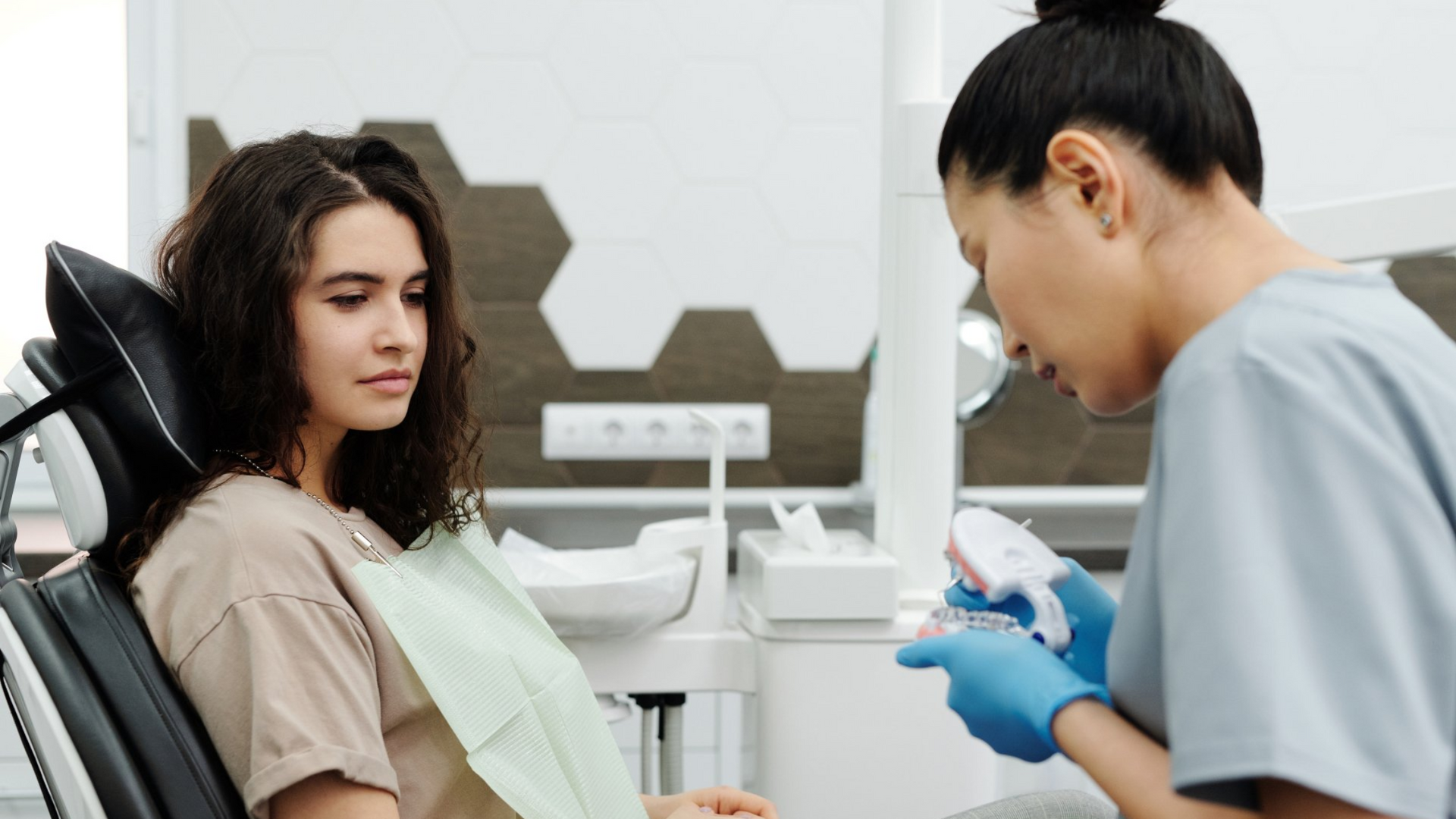 Dentist showing patient a model of mouth and teeth, showing details of the treatment plan