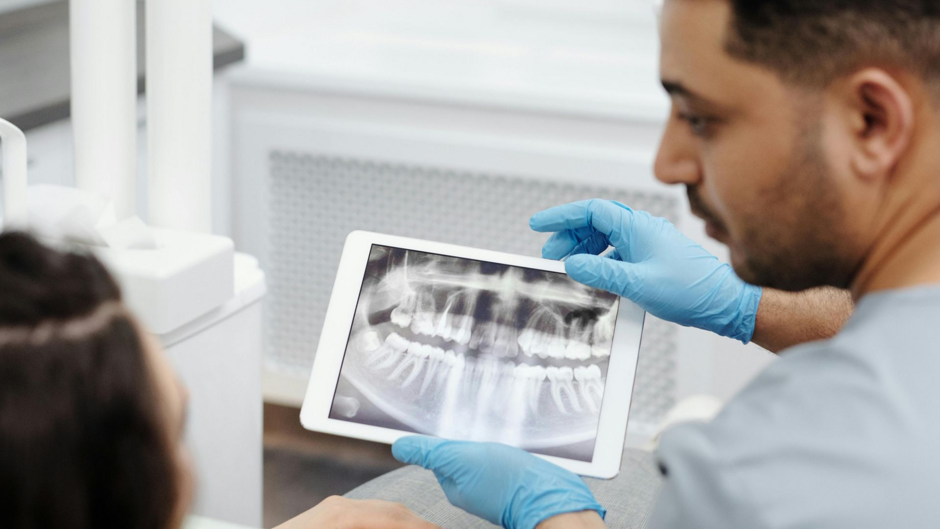 Dentist showing patient x-ray of mouth, discussing treatment plan