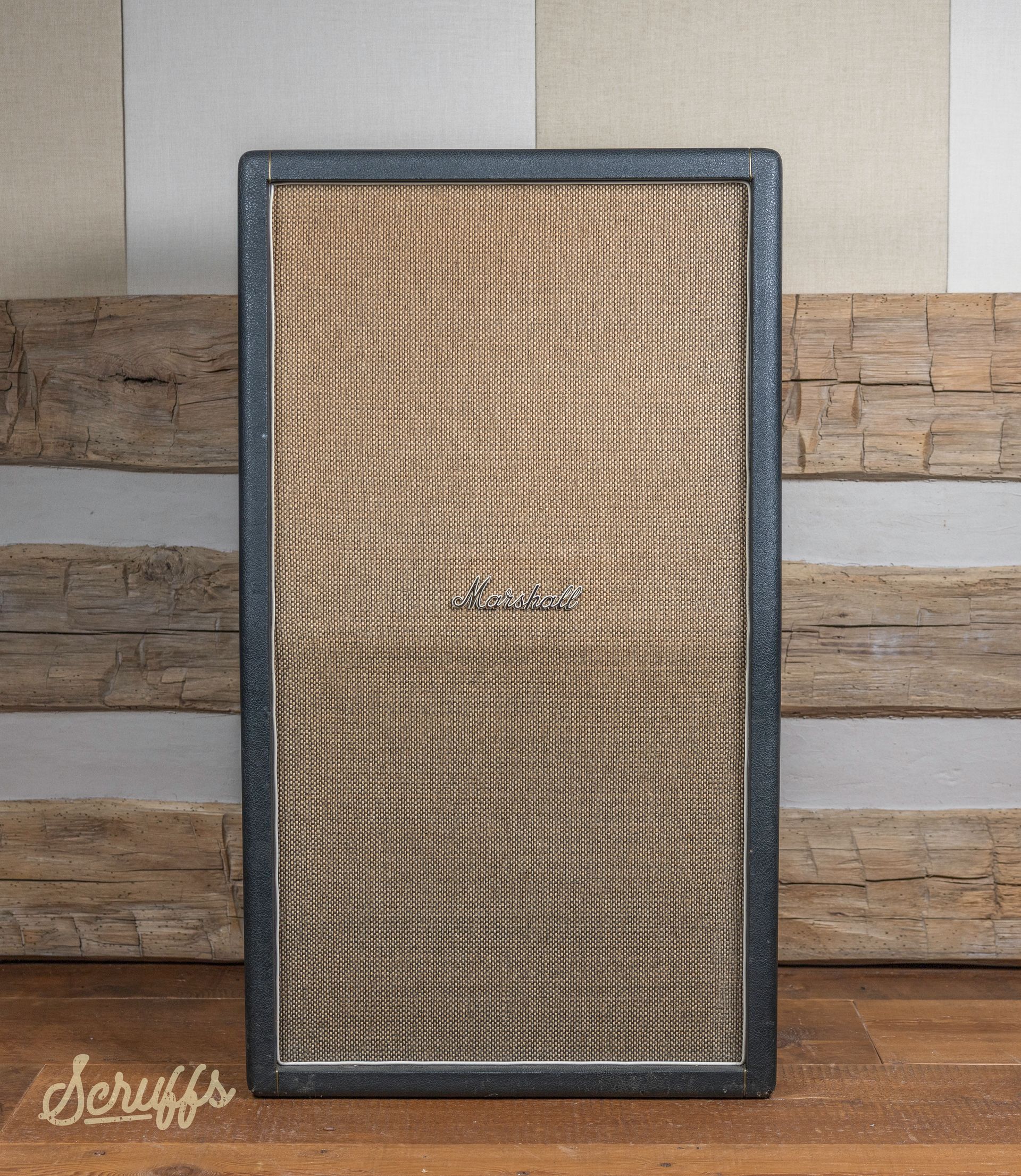 A guitar amplifier is sitting on a wooden table in front of a wooden wall ..