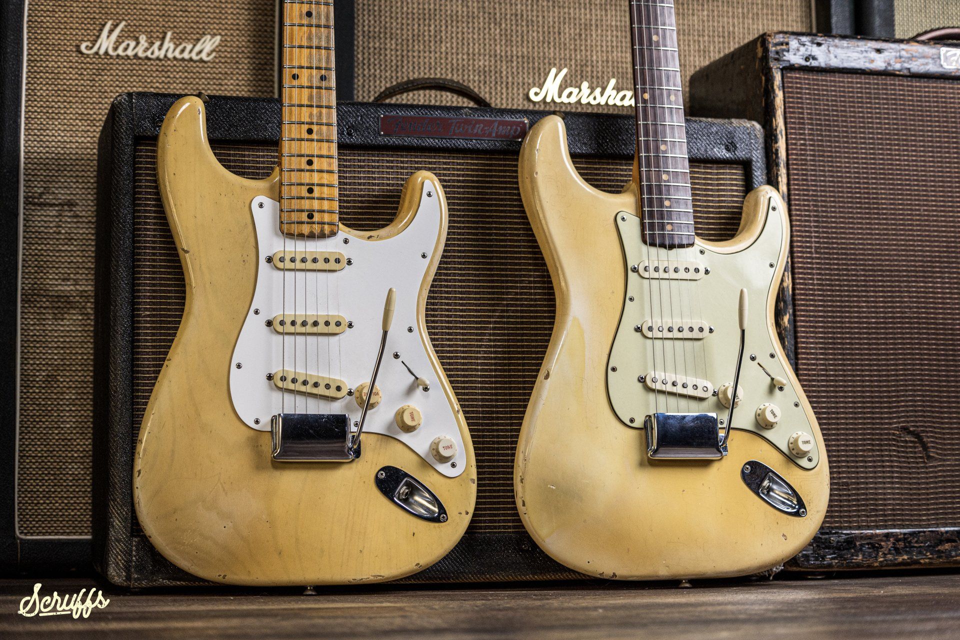 Two guitars are sitting next to each other in front of a fender amplifier.