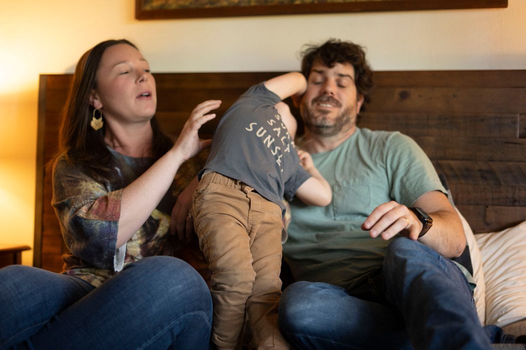 A man and a woman are sitting on a couch with a child.