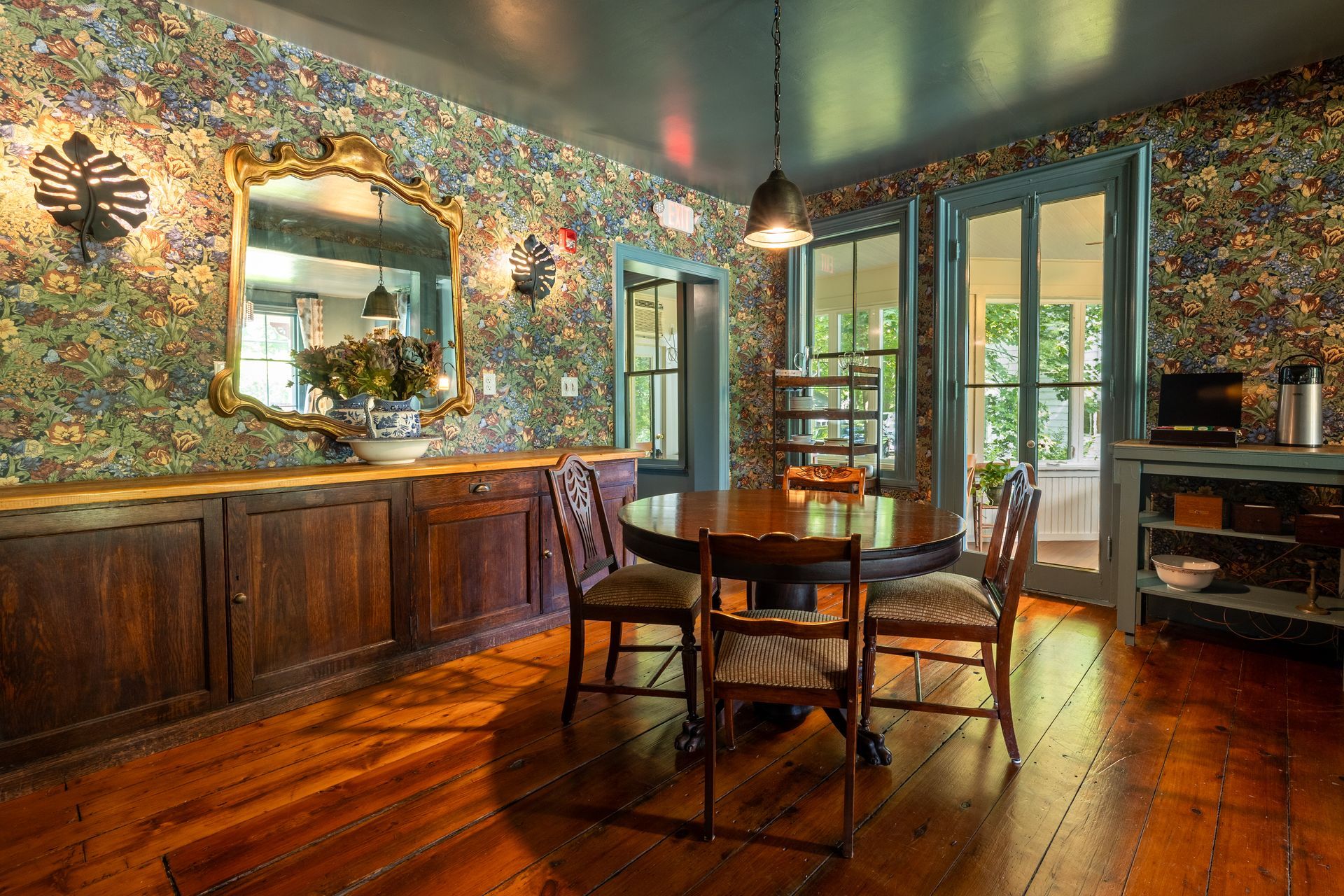 A dining room with a table and chairs and a mirror on the wall.