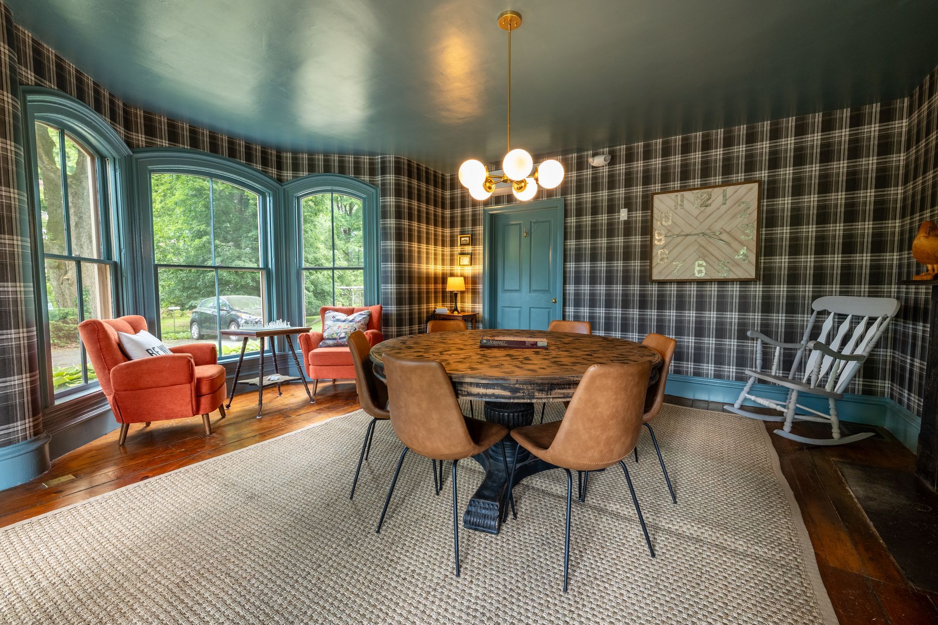 A dining room with a round table and chairs and a rocking chair.