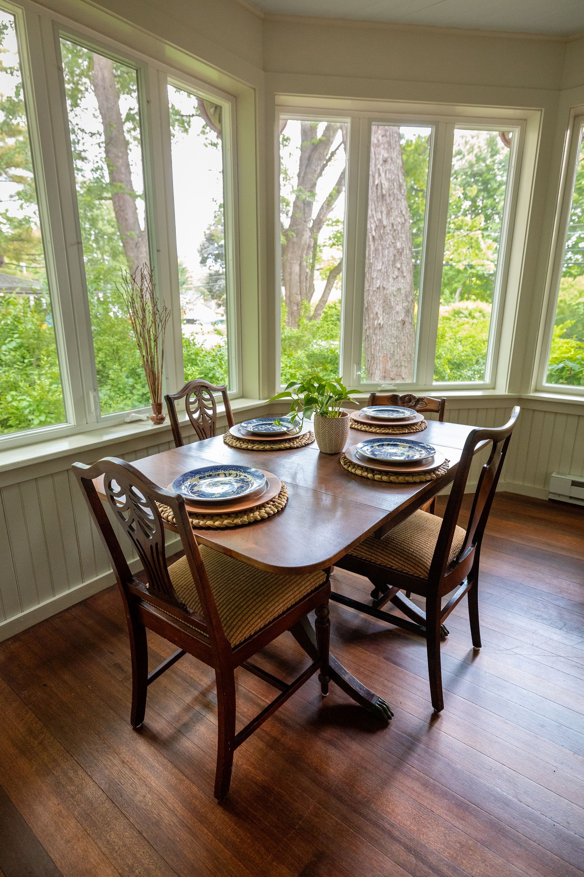 A dining room with a table and chairs and a lot of windows.