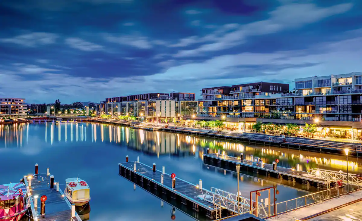 An aerial view of a marina at night with boats docked and buildings in the background.