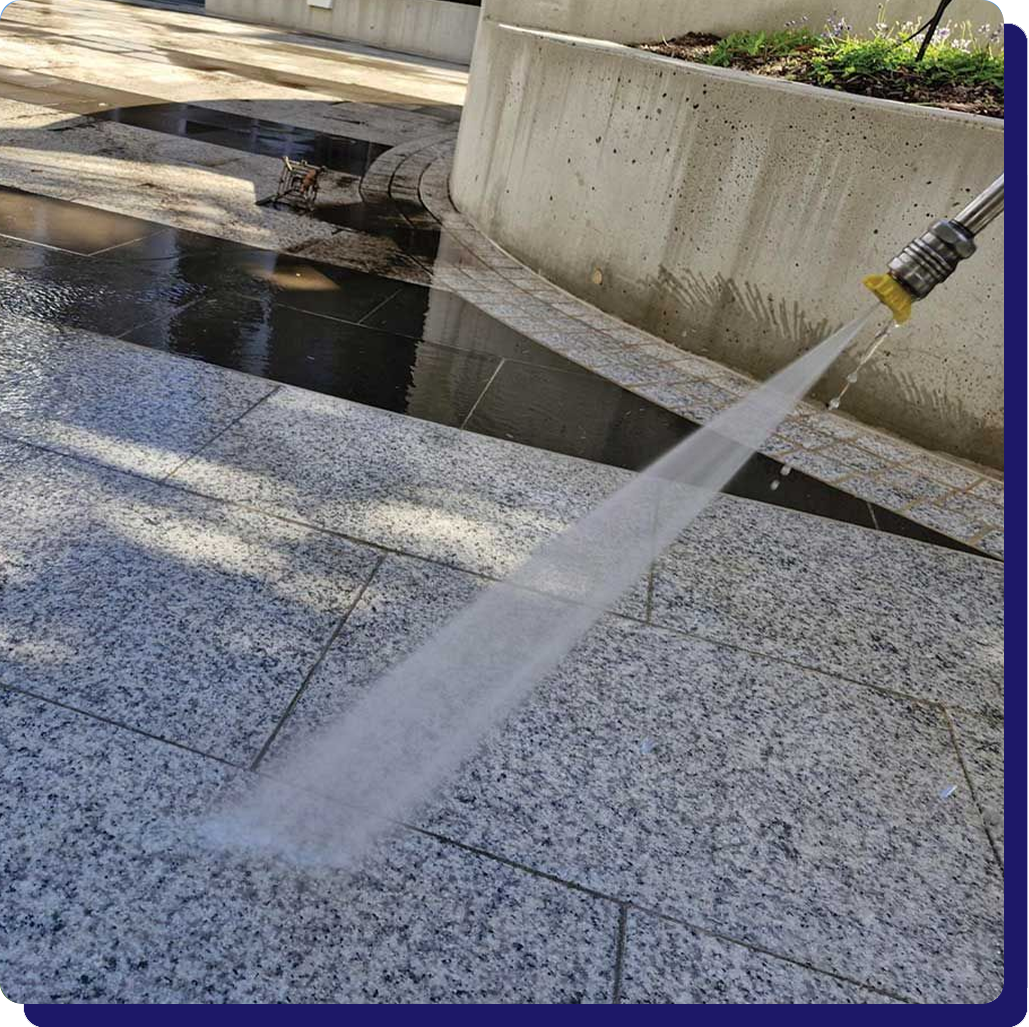 A person is using a high pressure washer to clean a tiled floor.