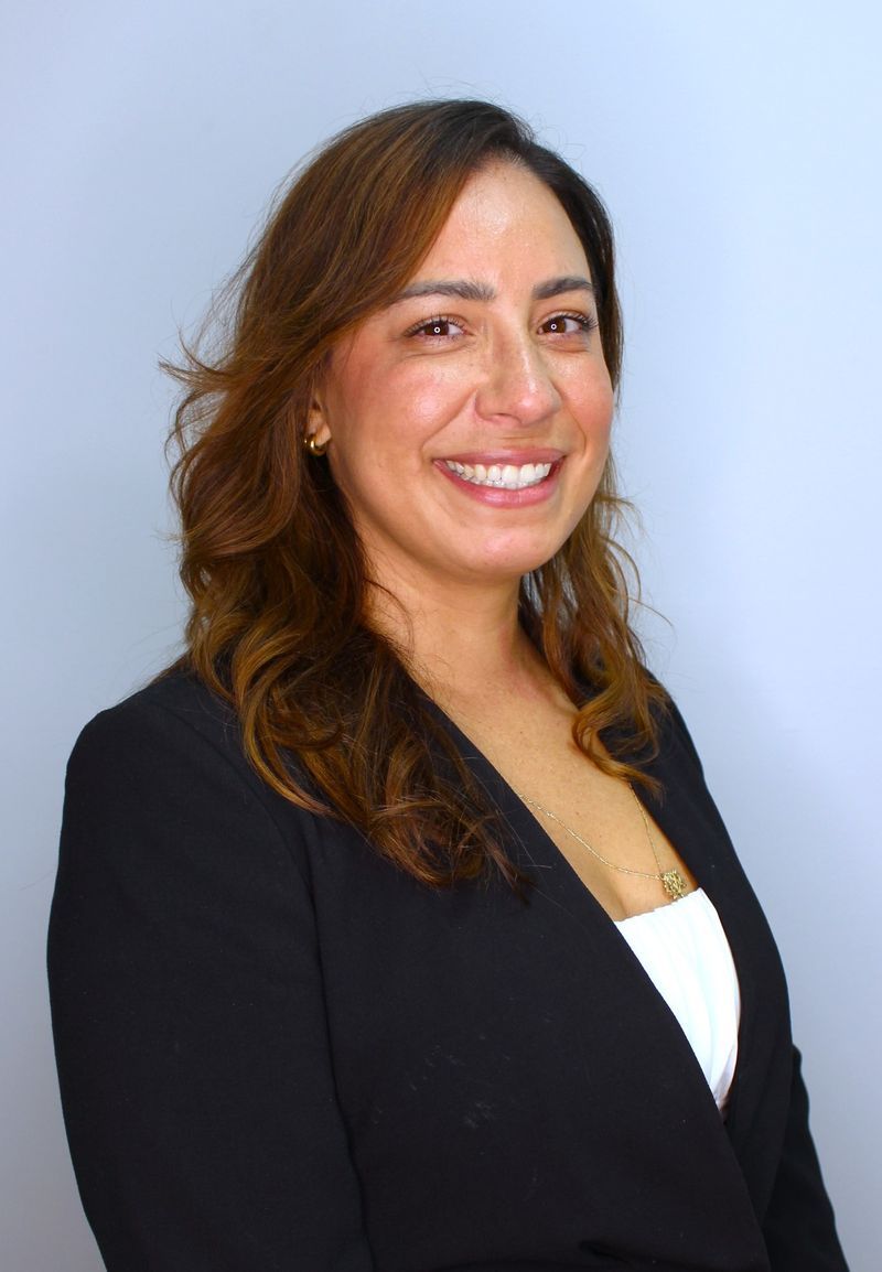 A woman in a black jacket and white shirt is smiling for the camera.