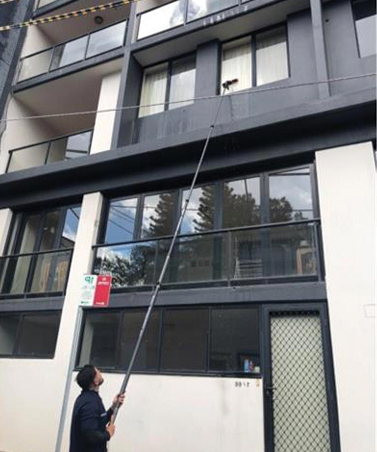 A man is cleaning the windows of a building with a hose.