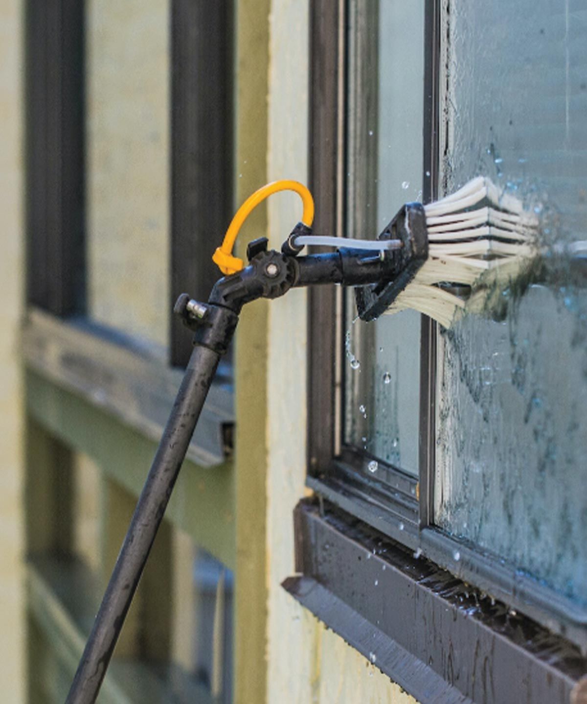 A person is cleaning a window with a brush.