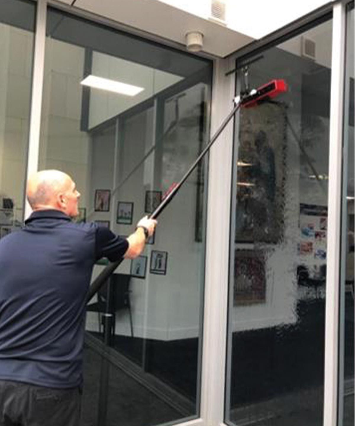 A man is cleaning a window with a long pole