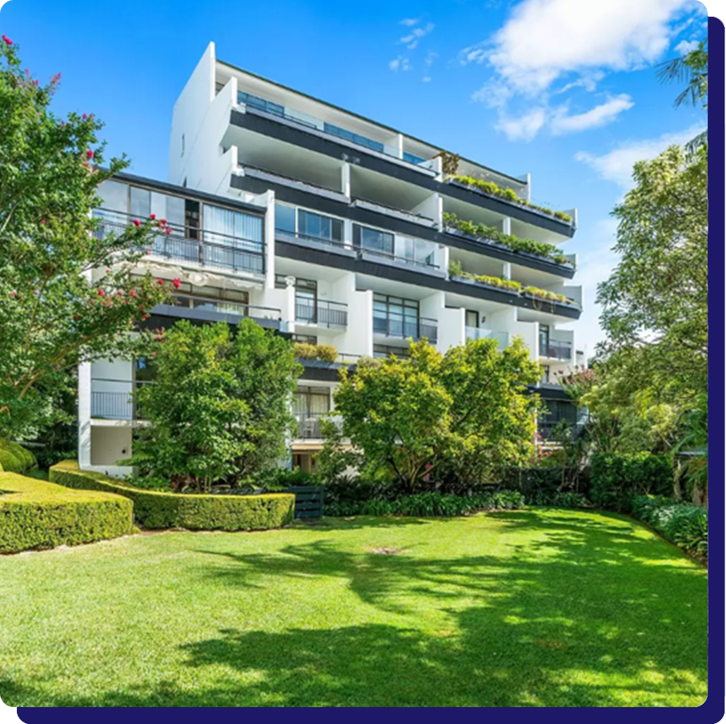 A large apartment building with a lush green lawn in front of it.