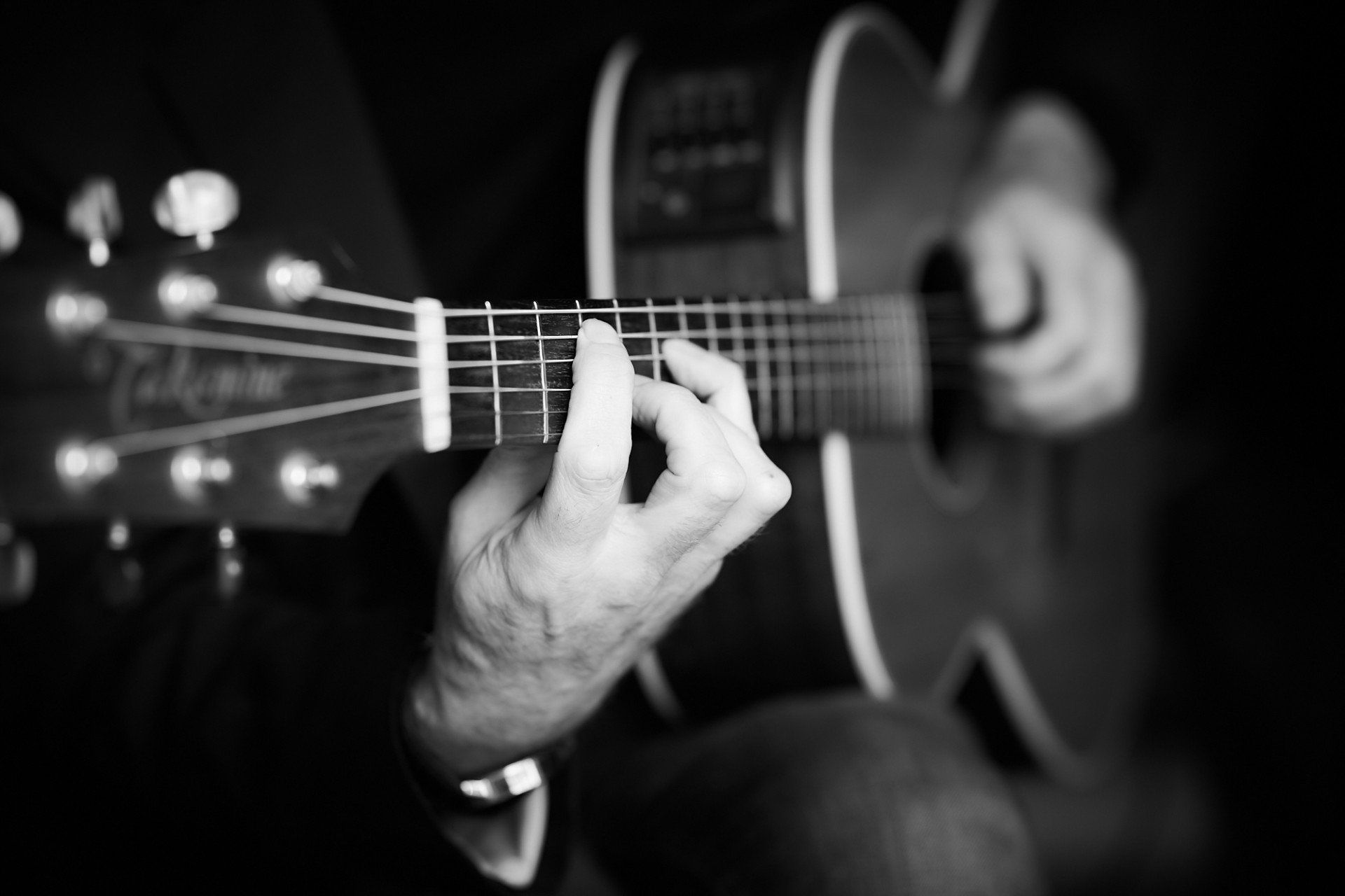 A guitarist's hands playing an acoustic guitar