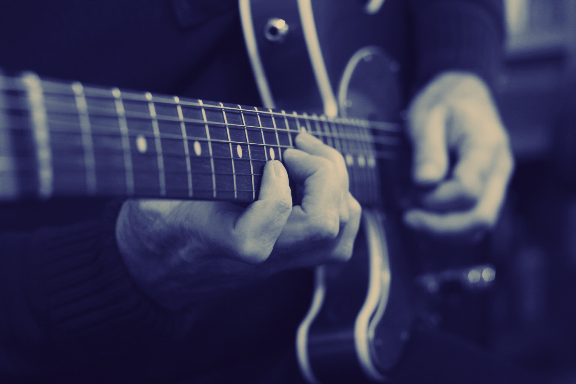 A guitarist's hands playing an electric guitar