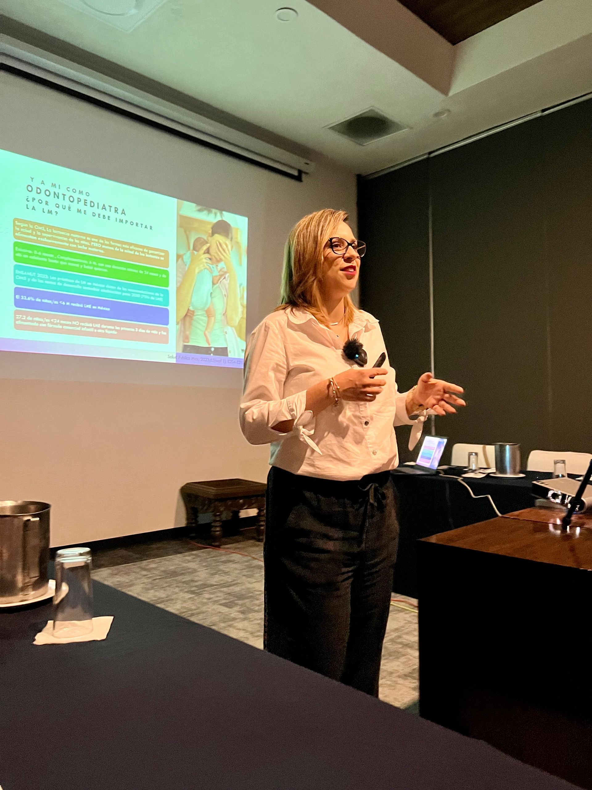 Una mujer está dando una presentación frente a una pantalla de proyección.