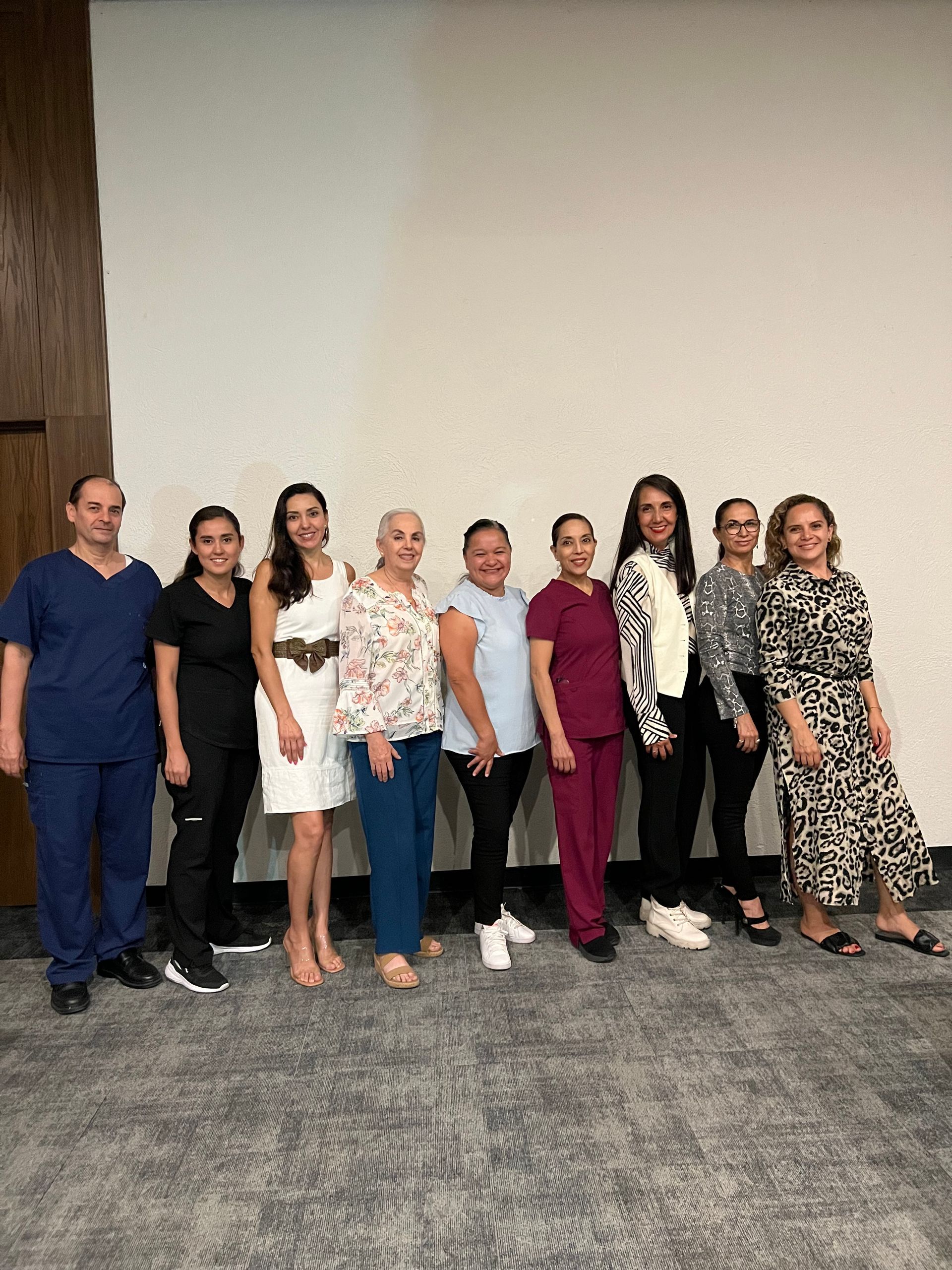 Un grupo de personas paradas una al lado de la otra frente a una pared.
