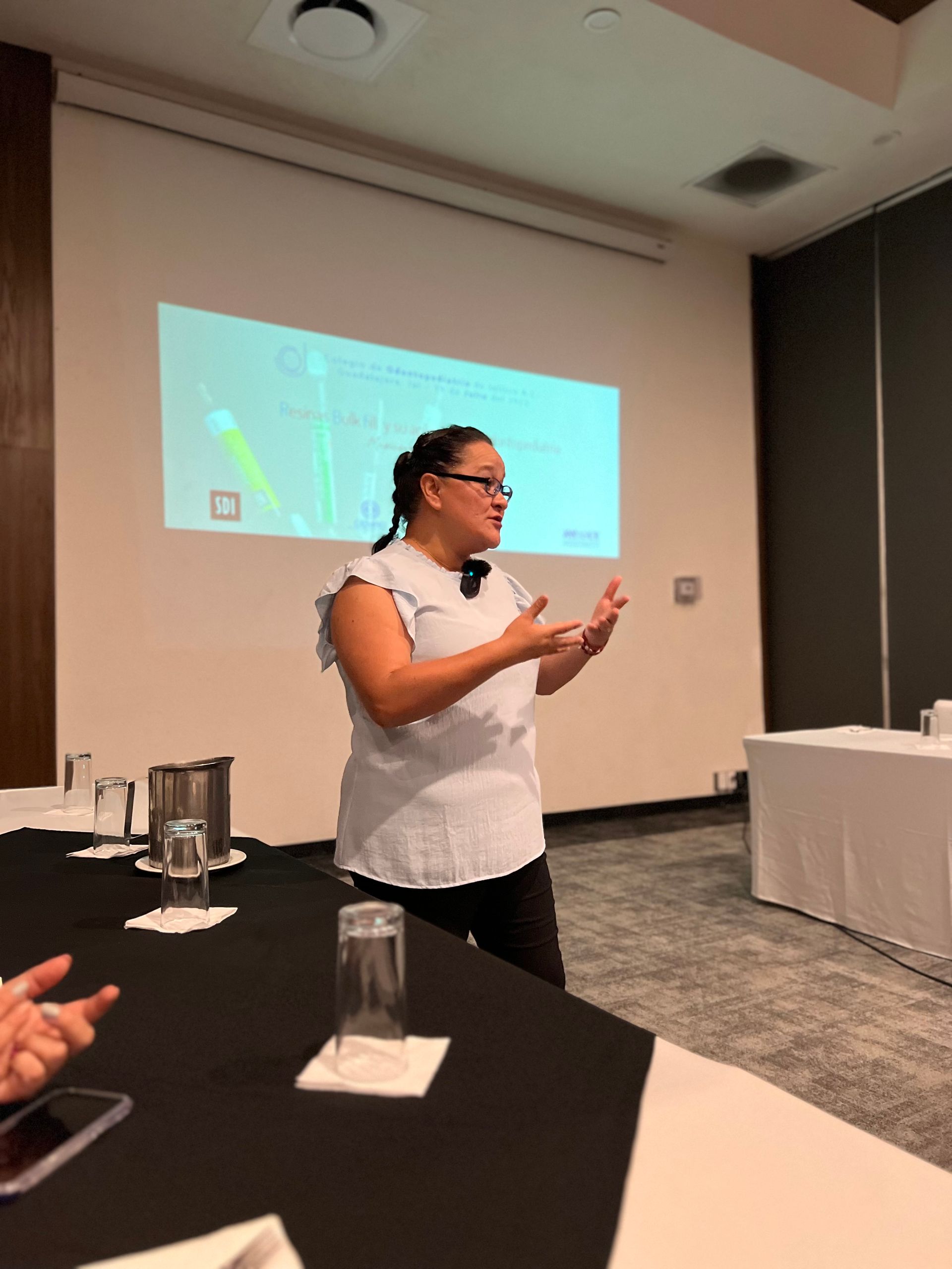 Una mujer está dando una presentación frente a una pantalla de proyección