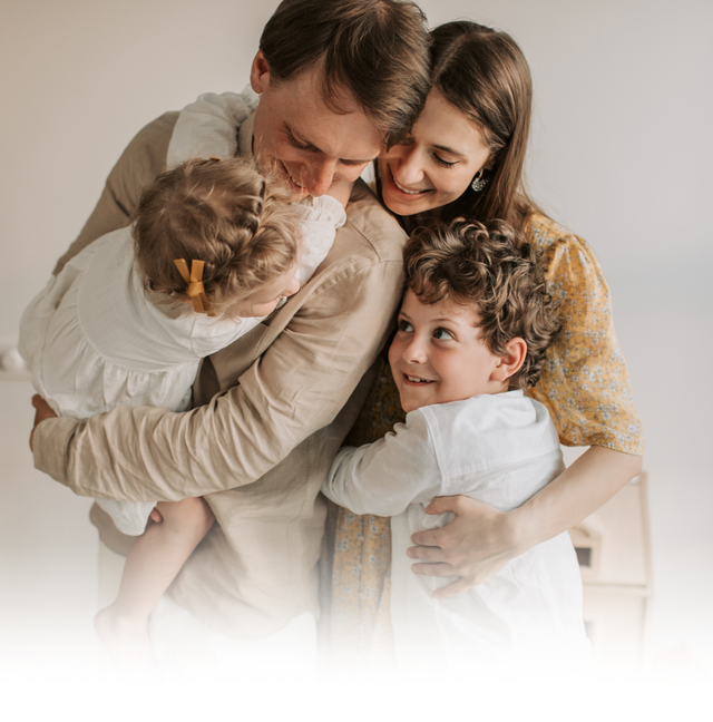 A family embracing each other in a warm, indoor setting, capturing a moment of affection and connection.