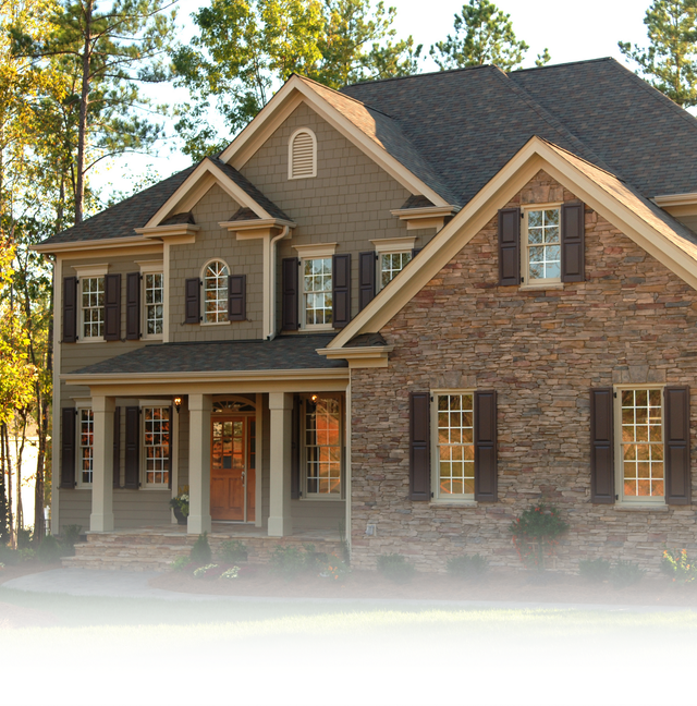 A two-story suburban home with stone and brown siding, a covered front porch, and dark shingled gabled roofs.