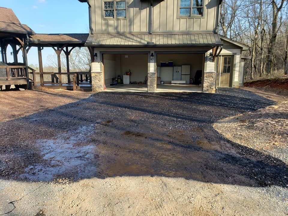 Driveway with newly paved asphalt in front of a house with a garage.