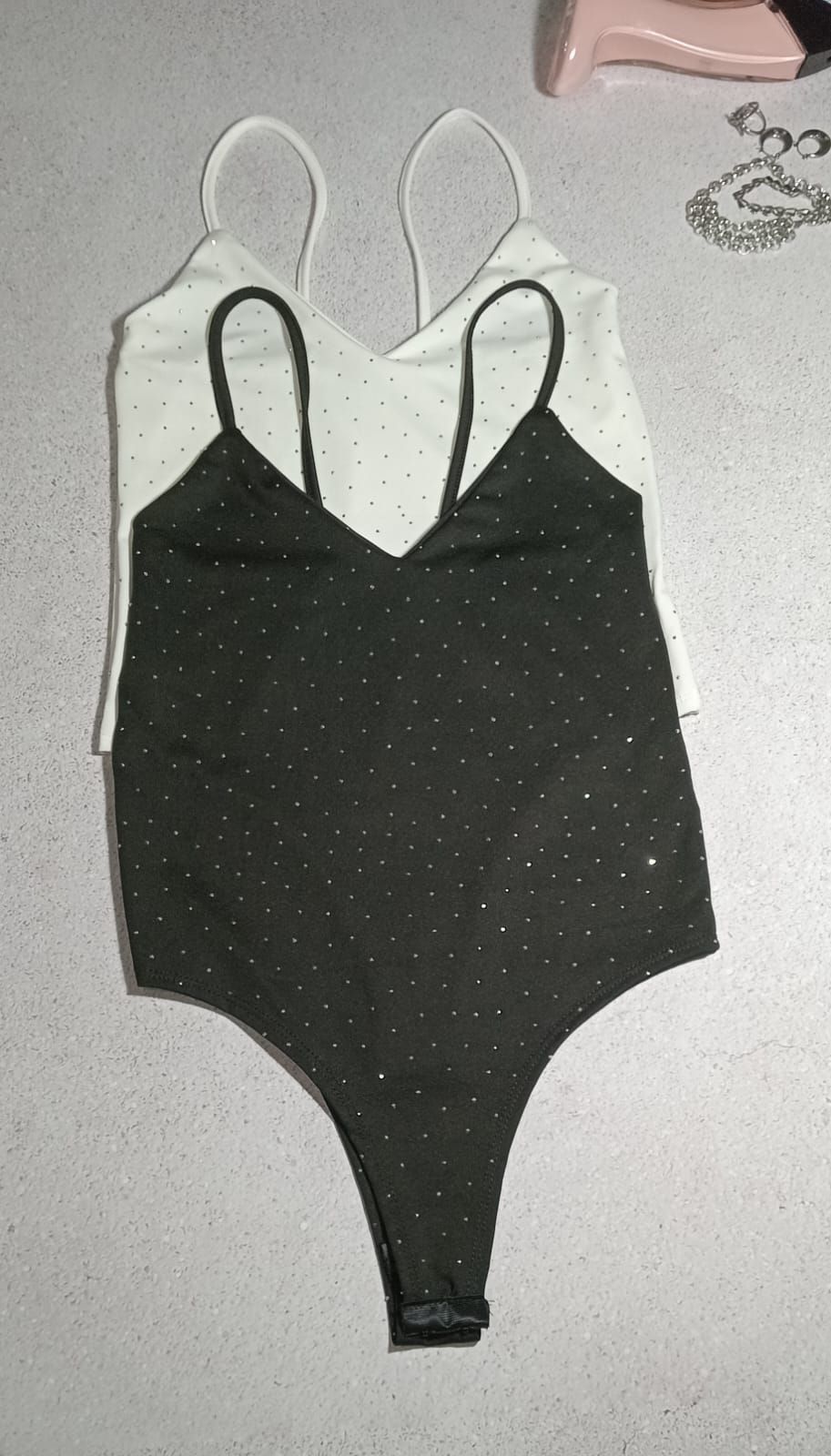 Traje brillante blanco y negro colocado sobre una superficie de color claro.