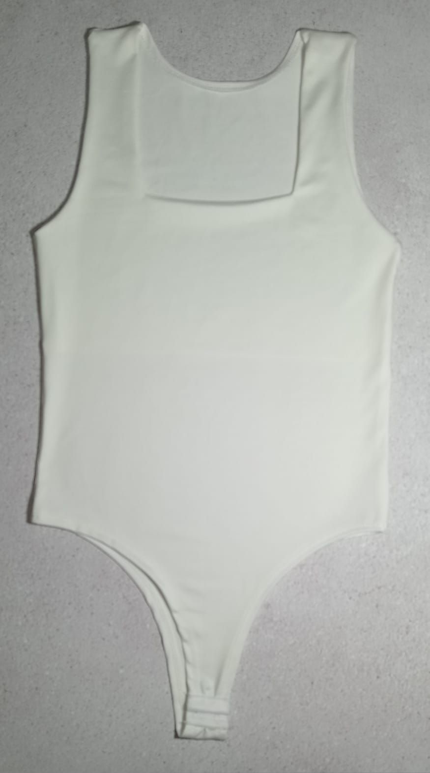 Body negro sin mangas con escote cuadrado, dispuesto plano sobre una superficie texturizada.