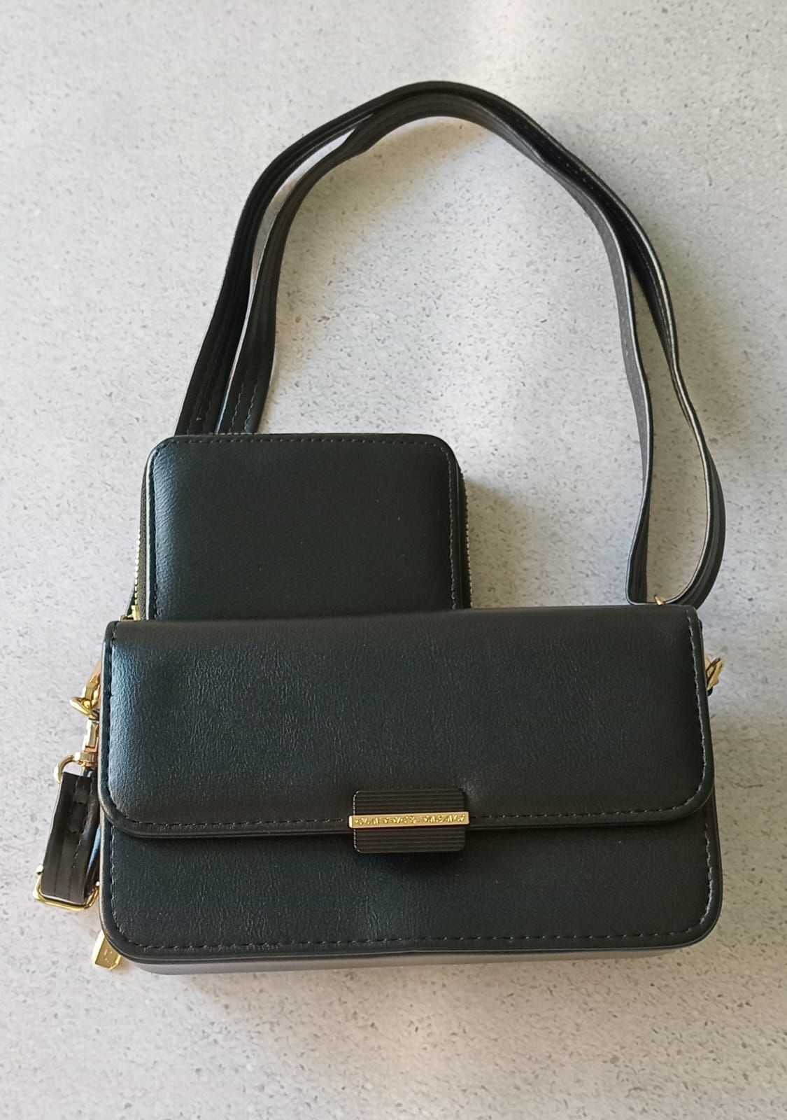 Bolso de mano negro con cartera a juego sobre superficie clara.
