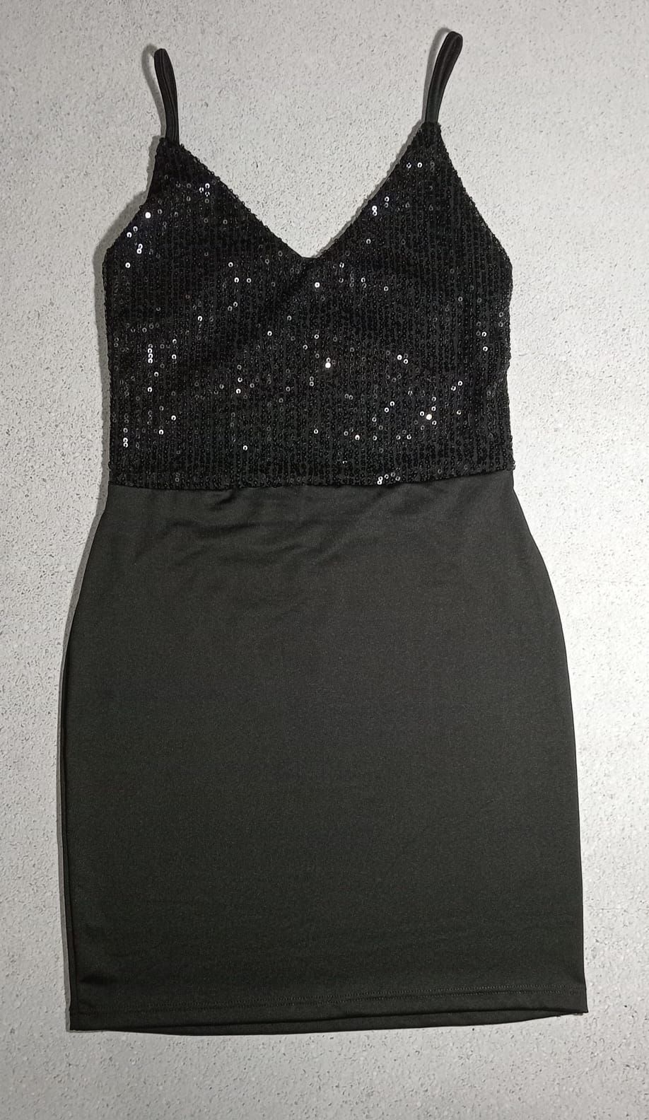 Vestido con corpiño de lentejuelas negras, tirantes finos y falda gris oscuro.