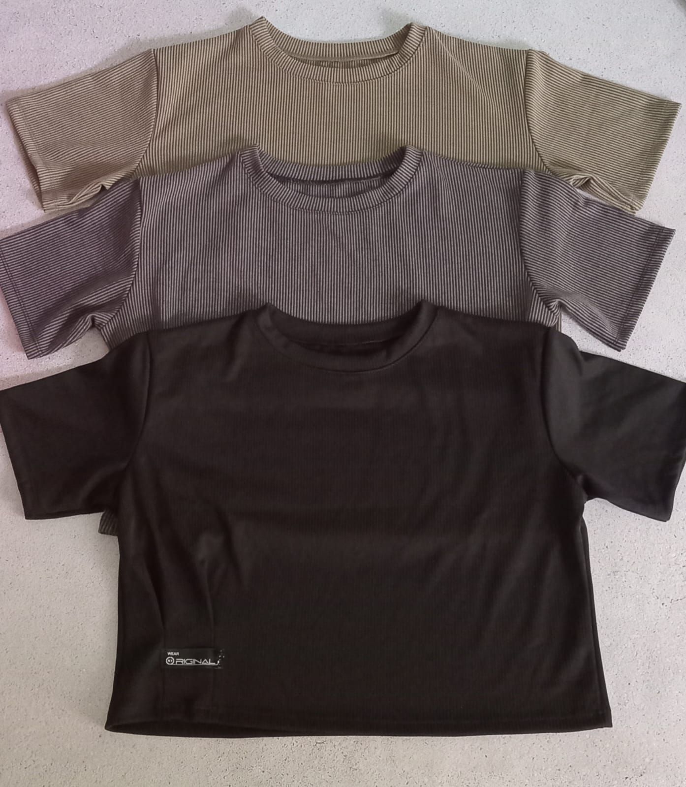 Top corto de canalé beige y pantalones cortos de mezclilla colocados sobre una superficie con gafas de sol y pendientes.